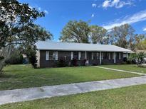 Charming single-story brick home with a metal roof, white trim, and a well-manicured lawn at 307 N Oak Ave, Fort Meade, FL 33841