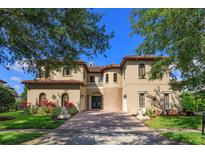 Stunning stucco home with red tile roof, manicured landscaping, and grand paver driveway at 5719 Emerson Pointe Way, Orlando, FL 32819