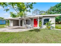 Charming single-story home with a covered carport, lush lawn, and a bright red front door at 704 Baywood Dr, Sanford, FL 32773