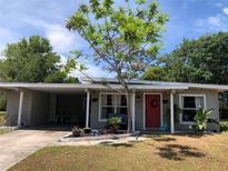 Charming single story home featuring a front yard, a red door with a wreath, and a covered carport at 704 Baywood Dr, Sanford, FL 32773