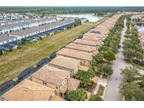 Expansive aerial view of a neighborhood featuring tile roofs, green spaces, and a tranquil lake at 8941 Rhodes St, Kissimmee, FL 34747