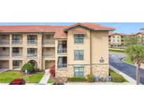 Attractive condo building featuring stone accents, a terracotta roof, and well-maintained landscaping at 912 Charo Pkwy # 214, Davenport, FL 33897