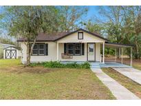 Charming one-story home with a covered carport, front porch swing, and well-maintained front yard at 119 E Central Ave, Bushnell, FL 33513