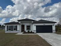 Charming single-story home with a dark gray garage door, a well-manicured lawn, and a welcoming entrance at 13566 Sw 43Rd Cir, Ocala, FL 34473