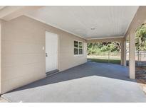 A covered carport showing a concrete foundation, a white exterior door, and a view of the yard beyond at 1797 31St Nw St, Winter Haven, FL 33881