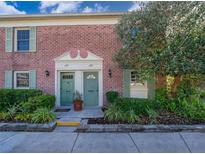 Charming brick townhome featuring twin entrances with green doors, lush landscaping, and a mature shade tree at 620 Georgetown Dr # 620, Casselberry, FL 32707