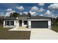 Modern home with a dark gray garage door, stone accents, and a well-maintained lawn at 171 Marion Oaks Trl, Ocala, FL 34473