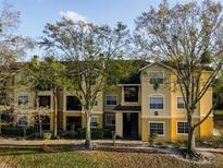 Attractive multi-level condo with a yellow exterior, mature trees, and well-maintained landscaping at 2600 Robert Trent Jones # 934, Orlando, FL 32835