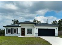 Charming single-story home with a black garage door, gray stone accents, and well-manicured lawn at 2703 Sw 162Nd Street Rd, Ocala, FL 34473