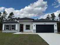 New construction shows off with gray and white exterior and black garage and roof on a sunny day at 4875 Sw 159Th Lane Rd, Ocala, FL 34473