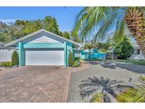 Charming home featuring a brick driveway, manicured bushes, lush palms, and a two-car garage at 721 Glenridge Way, Winter Park, FL 32789