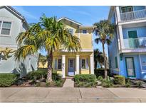 Charming yellow two-story home with blue trim, a well-manicured lawn, and vibrant tropical landscaping at 8005 Flip Flop Way, Kissimmee, FL 34747