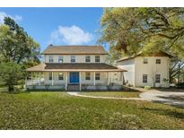 Charming two-story home featuring a full wrap-around porch and a bright blue front door at 9332 Windy Ridge Rd, Windermere, FL 34786