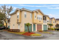 Inviting townhome exterior featuring a two-car garage and well-maintained landscaping at 12008 Villanova Dr # 112, Orlando, FL 32837