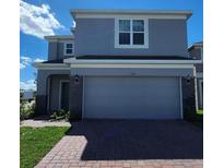 Two-story home showcasing brick-paved driveway, two-car garage and stone veneer accents at 1355 Berry Ln, Davenport, FL 33837