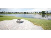 Beautiful backyard features a brick patio with a fire pit overlooking a tranquil lake at 14712 Eagles Crossing Dr, Orlando, FL 32837