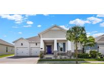 Charming single-story home with a manicured lawn, paver driveway and vibrant blue front door at 5499 Orange Orchard Dr, Winter Garden, FL 34787