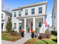 Charming two-story home featuring a well-manicured lawn and a welcoming front porch with a vibrant red door at 1073 Sadler Oaks Way, Winter Garden, FL 34787