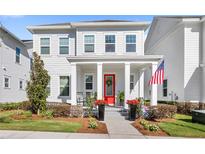 Charming two-story home featuring a well-manicured lawn and a welcoming front porch with a vibrant red door at 1073 Sadler Oaks Way, Winter Garden, FL 34787