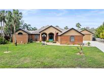 Beautiful brick home with a well-manicured lawn and mature palm trees in a desirable neighborhood at 448 Warrior Trl, Deltona, FL 32725