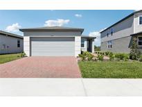 Charming single-story home with a brick driveway, landscaped yard, and attached two-car garage at 2513 Merseyside Ct, Haines City, FL 33844