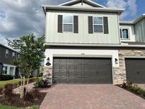 Two-car garage with a brick paver driveway and stone facade accents create curb appeal at 4315 Campsite Loop, Orlando, FL 32824