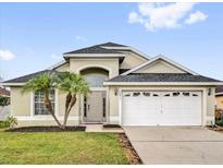 Charming single-Gathering home with a well-manicured lawn, an attached two-car garage, and decorative palm trees in the front yard at 5425 Bryce Canyon Dr, Kissimmee, FL 34758