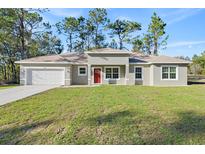 Charming single-story home with a well-manicured lawn and a bright red front door at 8015 Sw 133Rd Ln, Ocala, FL 34473