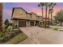 Townhome exterior featuring a brick driveway and a two-car garage at 8924 Azalea Sands Ln # 8924, Davenport, FL 33896