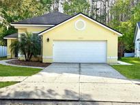 Charming yellow home featuring a well-maintained lawn and two-car garage at 10525 Satinwood Cir, Orlando, FL 32825