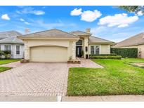 Charming one-story home with a brick driveway, well manicured lawn, and a beige tile roof at 10819 Woodchase Circle, Orlando, FL 32836