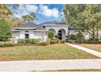 Charming home featuring an inviting entrance, manicured lawn, arched entryway, and mature landscaping at 1141 Sweet Heather Ln, Apopka, FL 32712