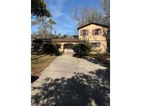 Charming two-story home featuring a tan exterior, brown shutters, a covered entry and a long driveway at 15523 Old Cheney Hwy, Orlando, FL 32828