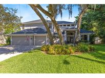 Charming two-story home with a well-manicured lawn and mature trees creating a picturesque setting at 235 Nob Hill Cir, Longwood, FL 32779