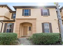 Charming two-story townhome featuring a welcoming arched doorway, shuttered windows and manicured front yard landscaping at 2511 Calabria Ave, Davenport, FL 33897