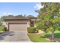 Charming single-story home with a brick driveway, two-car garage, and beautifully landscaped front yard at 556 Grande Dr, Davenport, FL 33837