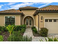 Charming home with a tile roof, beautiful landscaping, and a brick-paved walkway leading to an arched doorway at 9235 San Jose Blvd, Howey In The Hills, FL 34737
