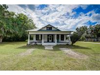 Charming home featuring a covered front porch, white siding, black window trim, and a beautifully landscaped lawn at 3512 Central Ave, Coleman, FL 33521