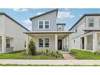 Charming two-story home featuring a quaint front porch, modern architectural details, and neatly manicured landscaping at 5106 Railroad Vine Aly, Winter Garden, FL 34787
