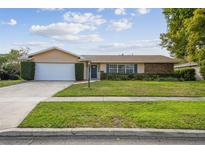 Charming single-story home featuring a manicured lawn, mature landscaping, and a two-car garage at 633 London Rd, Winter Park, FL 32792