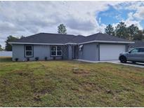 Charming one-story home with grey exterior, manicured lawn, and two car garage at 12913 Sw 82Nd Avenue Rd, Ocala, FL 34473