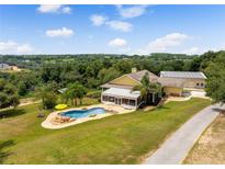 Stunning aerial view of the home, in-ground pool with a beautiful rock waterfall, and lush green landscape at 13045 Mountain Trail, Clermont, FL 34715