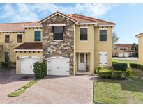 Charming townhouse showcasing a stone facade, red tile roof, and a brick driveway at 1411 Pacific Rd, Poinciana, FL 34759