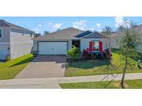 Charming single Gathering home with a brick driveway, tidy landscaping and bright red shutters at 1744 Wilson Prairie Cir, Groveland, FL 34736