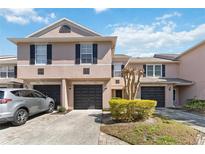 Exterior view of townhome featuring well-maintained landscaping, multiple garages, and neutral paint at 2913 Ashford Park Pl, Oviedo, FL 32765