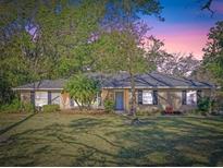 Charming single-story home featuring a well-manicured lawn, mature trees, and inviting blue front door at 33639 Wesley Rd, Eustis, FL 32736