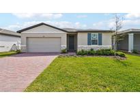 Charming single-story home boasts a manicured lawn, paver driveway, and stylish exterior accents at 3860 Giorgio Dr, Winter Haven, FL 33884