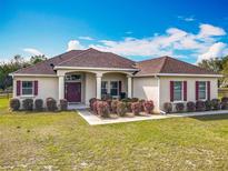 Charming single-story home featuring a well-manicured lawn and flower beds with a symmetrical design and elegant architectural details at 4560 Daugharty Rd, De Leon Springs, FL 32130