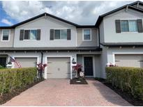 Charming townhome exterior with a brick driveway, one-car garage, and manicured landscaping at 1013 Flowing Tide Dr, Orlando, FL 32828