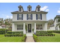 Stunning two-story home with a welcoming front porch, blue shutters, and professionally landscaped yard at 11402 Camden Loop Way, Windermere, FL 34786